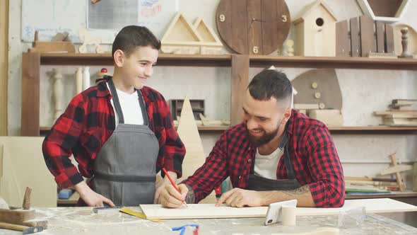 Dad Showing Video on Laptop To His Son Before Working with Wood Together