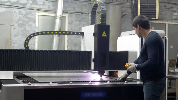 Engineer Worker Controls the Cutting of Metal Plates alt