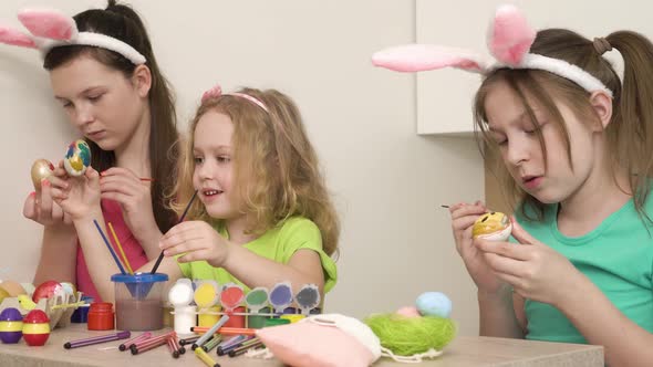 Three Girls Friends Decorate with Paint and Brushes Chicken Eggs