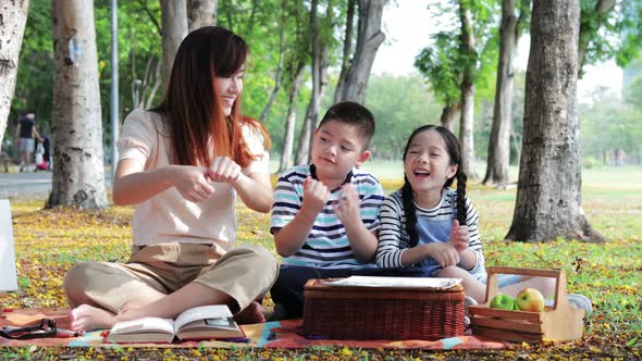 A single mother with two children, son, and daughter drawing a picture together in park