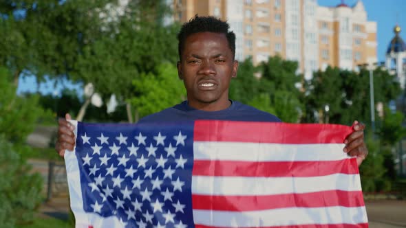Portrait AfroAmerican Man Holding American Flag Looks Camera Says USA in Summer alt