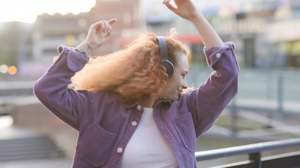 Woman dancing to music from headphones in the city
