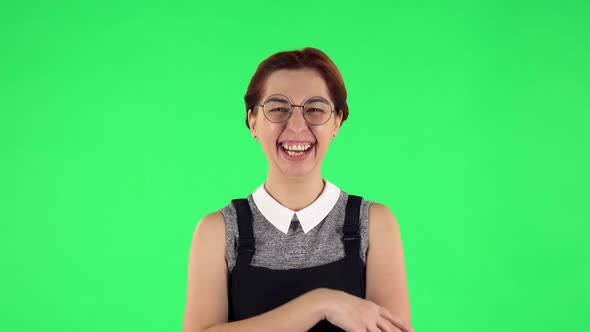 Portrait of Funny Girl in Round Glasses Communicates with Someone in a Friendly Manner. Green Screen alt