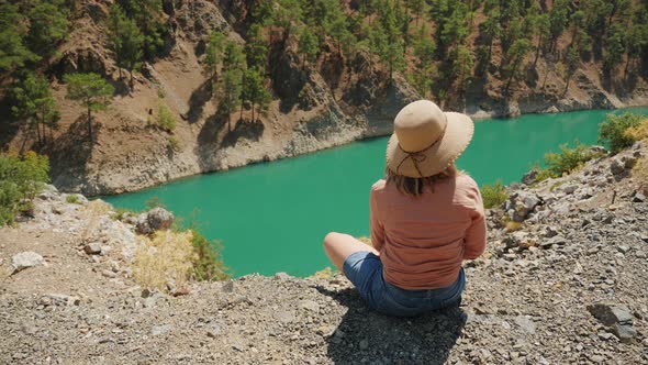 A Woman Sitting on the Edge of a Mountain Overlooking a Zamanti River alt