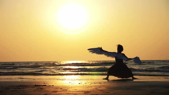 Silhouette of Young Girl with Wings Dancing at Sunset in Slow Motion