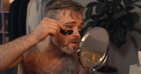 Handsome Mature Bachelor Plucking Eyebrows While Sitting in Front of mirror, Bearded Guy in 40s  alt