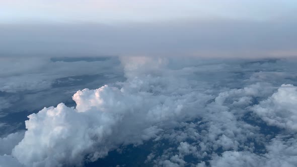 COCKPIT VIEW, DAWN- High altitude cruising over cumulonimbus and altocumulus clouds alt