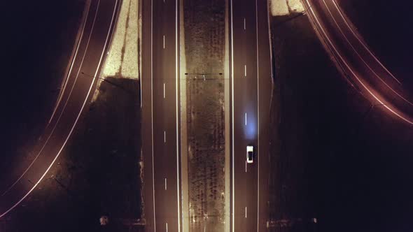 Top aerial shot of night traffic on a highway showing cars and lanes of light with bridges