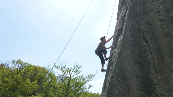 Strong Male Climber Climbing Steep Wall of Rocky Mountain alt