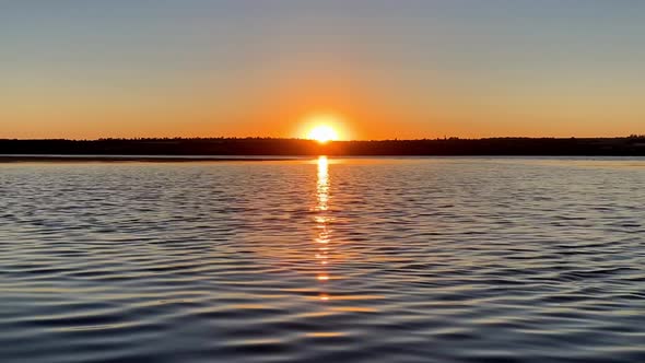 Sunrise over the river near the shore. Rising sun in clear sky. Timelapse