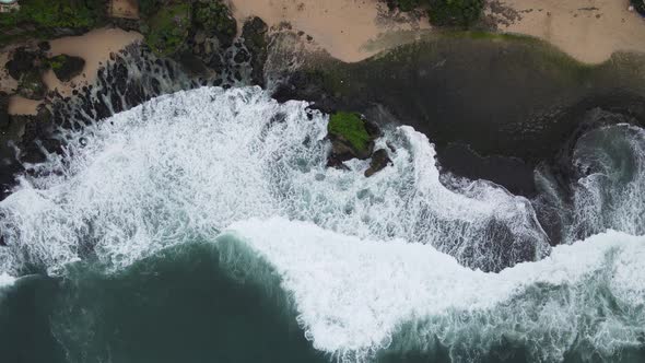 Top down aerial view of giant ocean waves crashing and foaming in coral beach alt