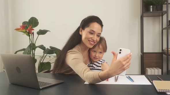 Mom and Her Little Daughter Take Selfies While Working in the Home Office alt