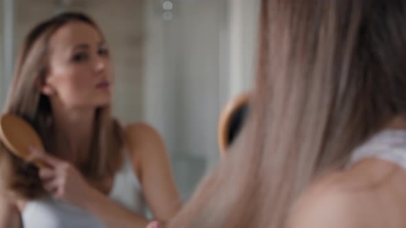 Caucasian woman brushing hair in the bathroom. Shot with RED helium camera in 8K. alt