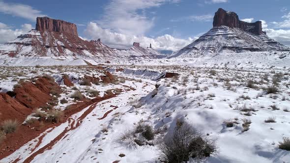 Flying over desert landscape covered in snow through wash alt
