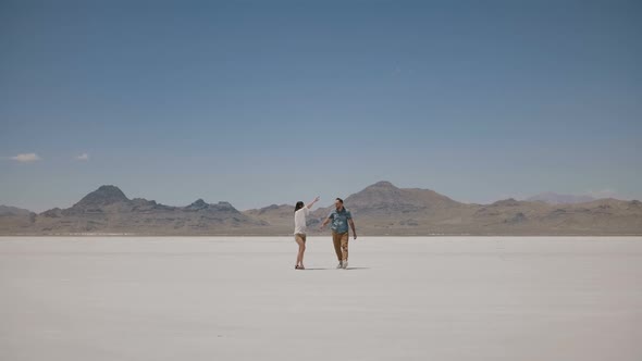 Back View Young Man Walks Towards Beautiful Woman Standing and Posing in the Middle of Sunny Hot alt