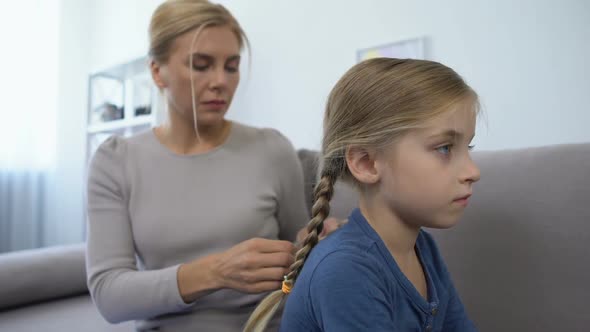 Caring Mother Making Braids and Combing Hair of Pretty Little Daughter, Family