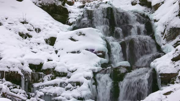 Small Streams of Cold Water Flow Among the Stones Covered with Snow alt