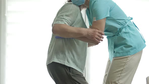 Doctor or Nurse is Helping an Elderly Woman to Get to Her Feet alt