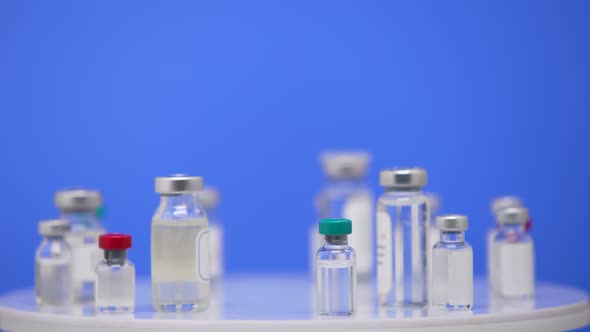 Coronavirus Vaccine in Ampoules Close Up on a Laboratory Table Blue Background alt