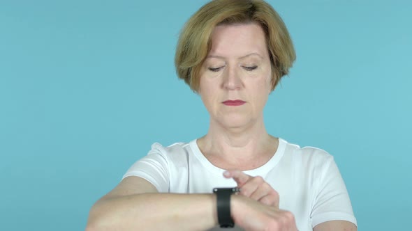 Senior Woman Using Smartwatch Isolated on Blue Background alt