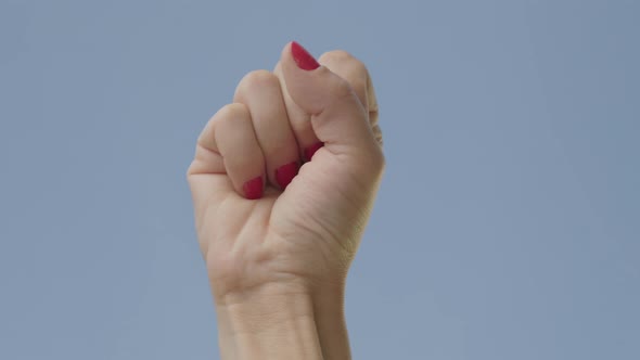 Close-up of Female Fist Raising Up at the Background of Clear Blue Sky. Unrecognizable Woman Showing alt