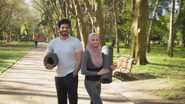 Front View of Smiling Muslim Man and Charming Woman in Hijab Standing Together alt