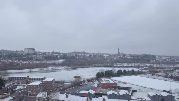 High dolly forward drone shot of a snowy Exeter as a train passes by alt
