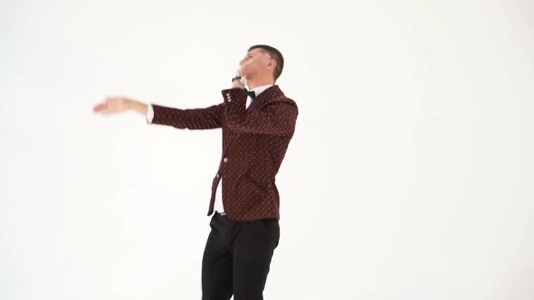 humorist in dark suit is parodying the body movements of a dancing person at a party alt