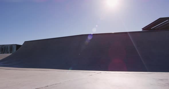 Caucasian man riding and jumping on skateboard on sunny day alt