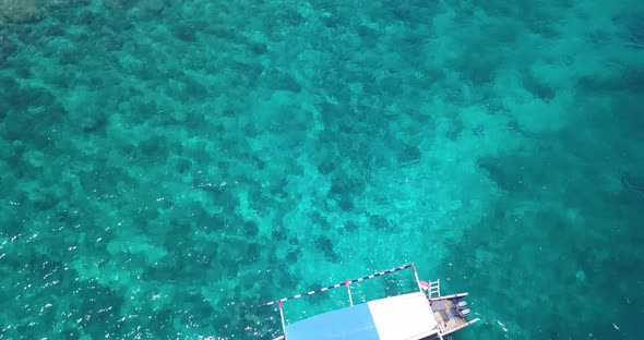 Indonesian fishing boat in turquoise water over beautiful coral reef, aerial