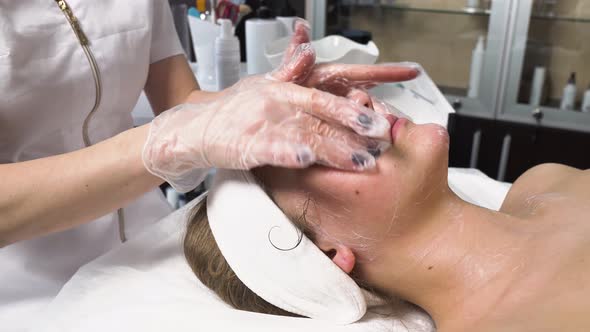 The Cosmetologist Cleanses the Client Face with a Gel in the Beauty Salon