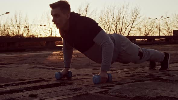 Young and fit man having evening workout outdoor. Urban sunset background. alt