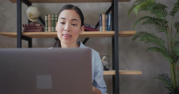 Close Up Portrait of Smiling Asian Teacher Conducts an Online Lesson Using Laptop alt