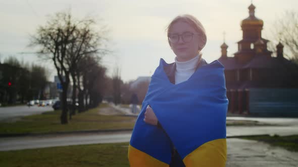 Portrait of a Joyful Ukrainian Woman Holding a Ukrainian Flag and a Sign alt