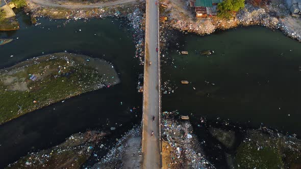 Aerial birdseye static shot of bridge over polluted river, Vietnam alt