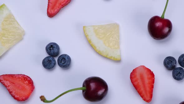 Rotation Background of Blueberries Strawberries Cherries and Lemon Slices on a White Background the