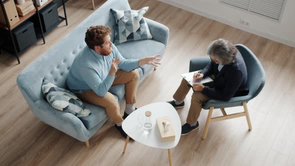 High Angle View of Men Psychologist and Patient Talking Sitting in Modern Office alt