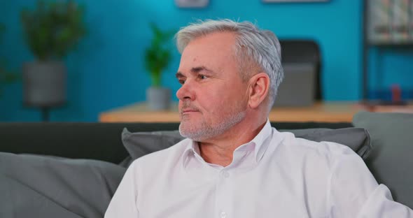 Portrait of Gloomy Mature 60s Gray Haired Man Posing at Home or Retirement House alt