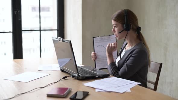 Young woman leads a remote meeting via laptop and shows graphs of growth alt
