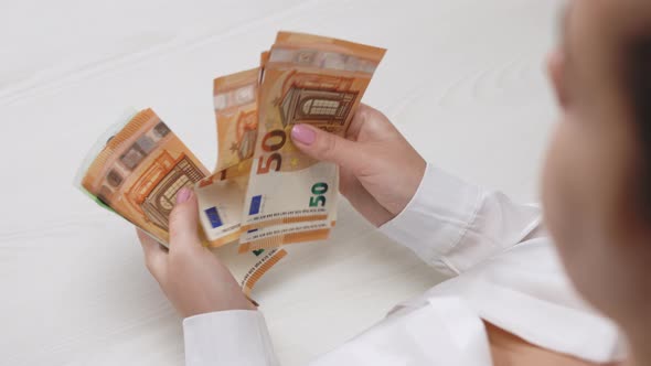 Close-up of Female Hands Counts a Bundle of 50 and 100 Euro Banknotes