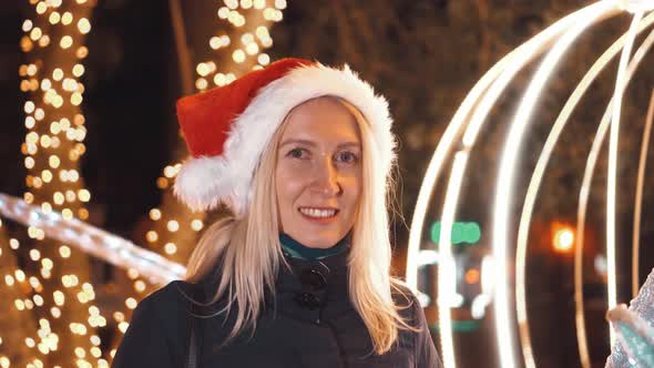 Portrait of a woman smiling at the camera and playing in a Santa hat alt