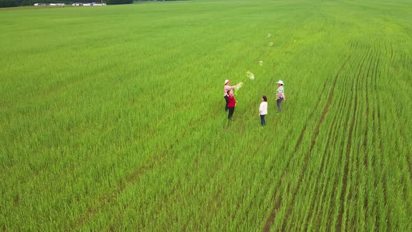 Adults Go and Blow Bubbles on a Green Field in Four alt