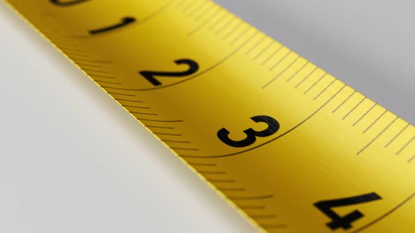 Camera moves along the yellow tape measure in endless loop. Close-up shot. alt
