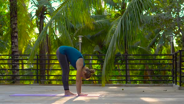 Young Woman Doing Exercises on a Roof of a House in Tropics alt