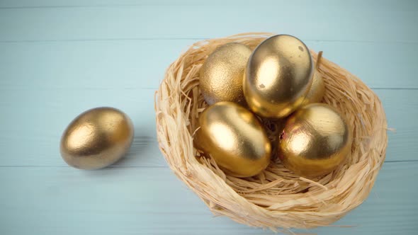 Easter Eggs Painted in Gold Color on Blue Wooden Table Close Up