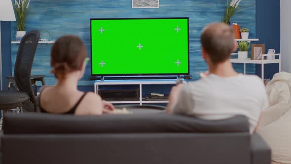 Static Tripod Shot of Couple Having a Snack While Looking at Green Screen Tv Watching a Movie alt