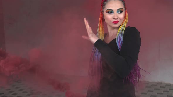 A Girl in a Simple Black Dress with Colored Braids and Rainbow Makeup Posing in Red Thick Smoke in a alt