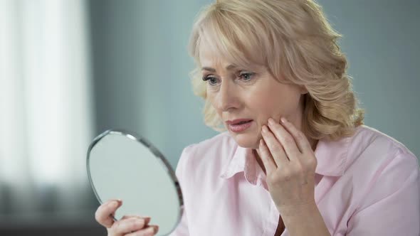 Sad Woman Looking at Face Reflection and Crying, Unhappy With Wrinkled Skin alt