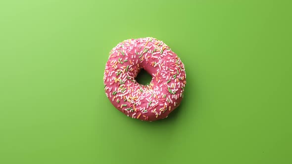 Top View Rotating Pink Glazed Donut Pastry Isolated on Green alt