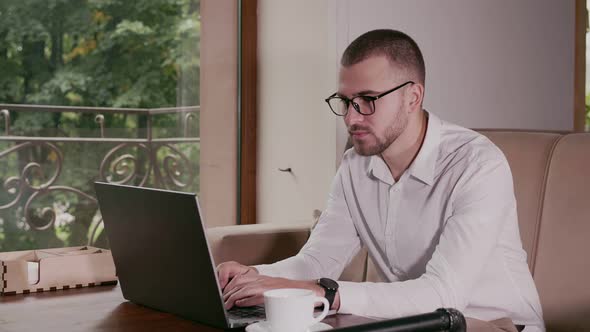 Businessman Typing on Laptop in Coffee